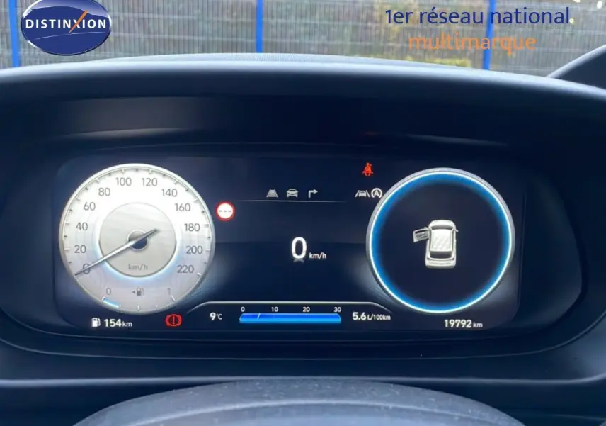 Tableau de bord numérique de la Hyundai i20 2025, affichant vitesse, consommation et porte ouverte, vue frontale rapprochée.