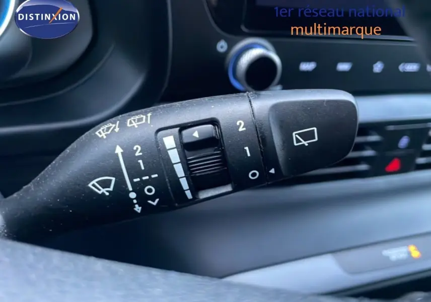 Gros plan sur la commande d’essuie-glace à gauche du volant dans l’habitacle d’une Hyundai i20 blanc Atlas 2025.