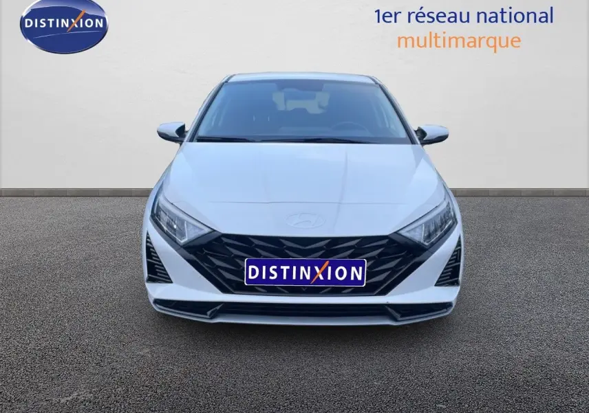 Vue frontale d'une Hyundai i20 2025 blanche Atlas avec calandre noire et phares LED distinctifs.
