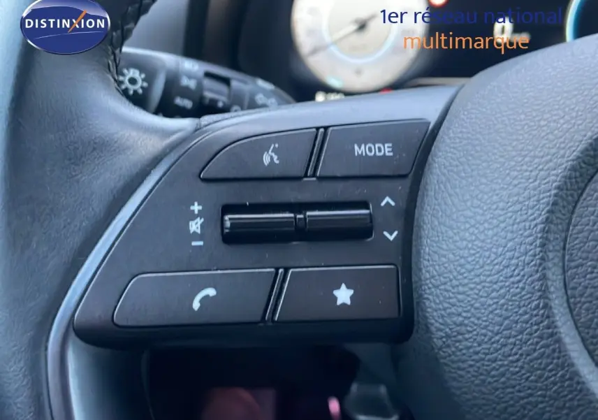 Gros plan sur les commandes multifonctions à gauche du volant en cuir noir d'une Hyundai i20 blanc atlas 2025.