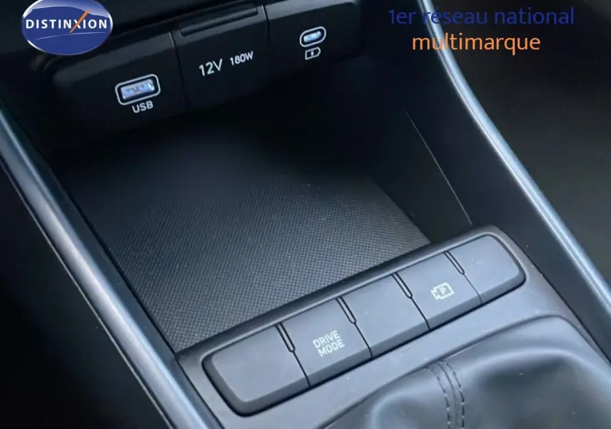 Gros plan sur la console centrale de la Hyundai i20 blanche avec boutons Drive Mode et frein à main électrique.
