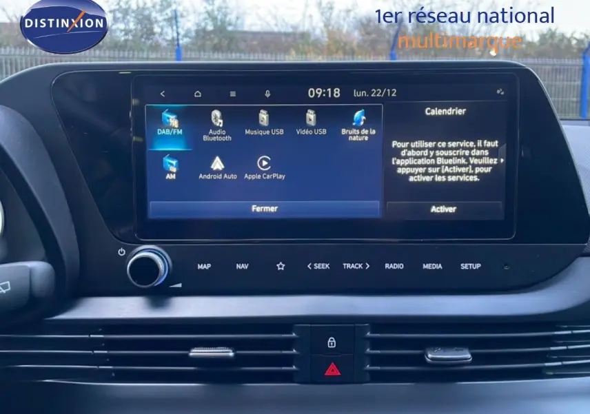 Vue rapprochée de l’écran tactile central de la Hyundai i20 blanche, affichant les options multimédia et connectivité.