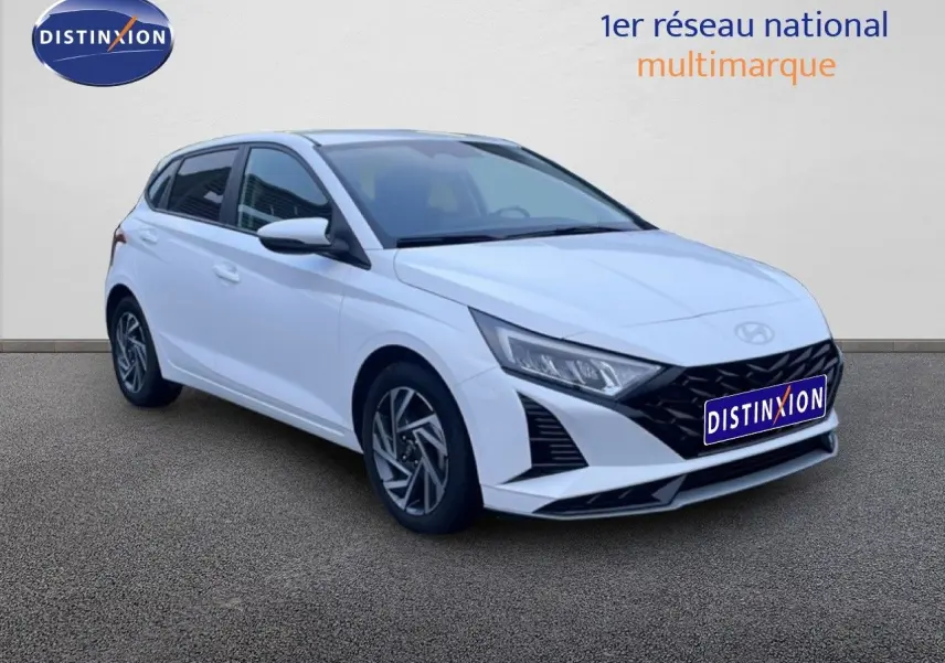 Vue 3/4 avant d’une Hyundai i20 blanche Atlas 2025 avec calandre noire et jantes alliage distinctives.