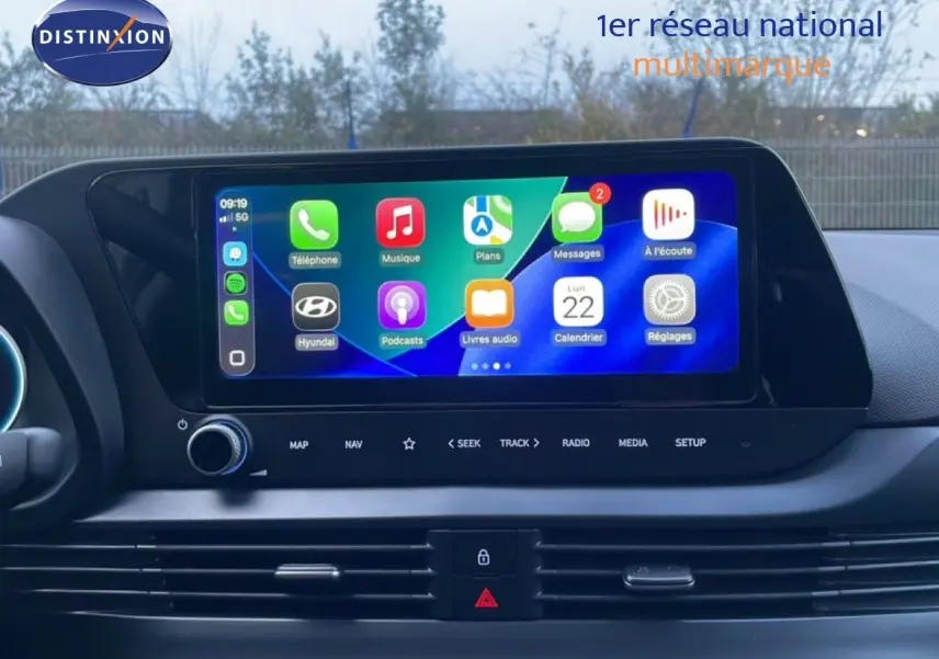 Vue rapprochée de l’écran tactile central de la Hyundai i20 blanche, affichant les applications connectées.