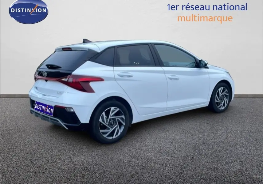 Vue 3/4 arrière droite d'une Hyundai i20 blanche Atlas avec toit noir et jantes alliage distinctives.