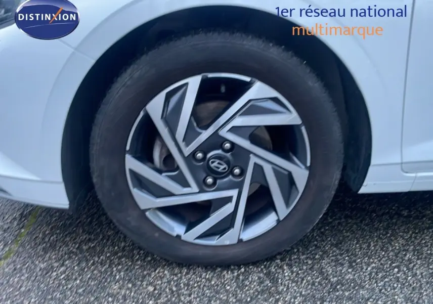 Gros plan sur la roue avant droite d'une Hyundai i20 blanche Atlas, mettant en valeur la jante au design géométrique.