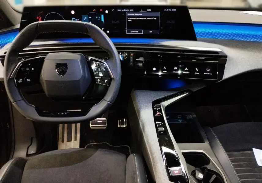 Vue intérieure frontale du Peugeot 3008 Hybrid 145 GT 2025, tableau de bord numérique et volant compact cuir noir avec surpiqûres Iced Clay.