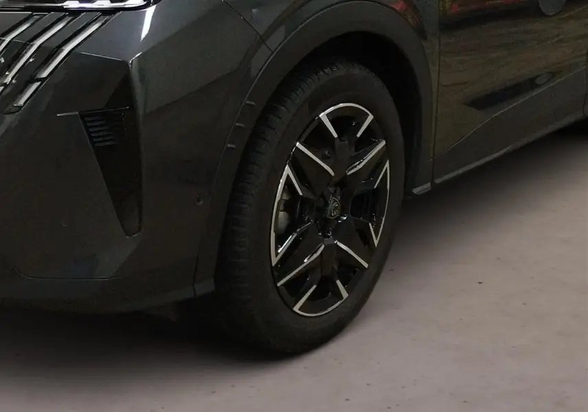 Gros plan sur la roue avant gauche du Peugeot 3008 Hybrid gris Titane avec jante alliage noire et argentée.