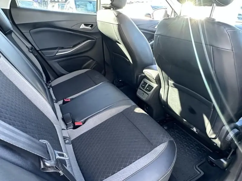 Vue intérieure arrière droite de l’Opel Grandland X 1.6 D 120 Innovation 2018, sièges noirs et gris avec appuie-têtes et ceintures visibles.