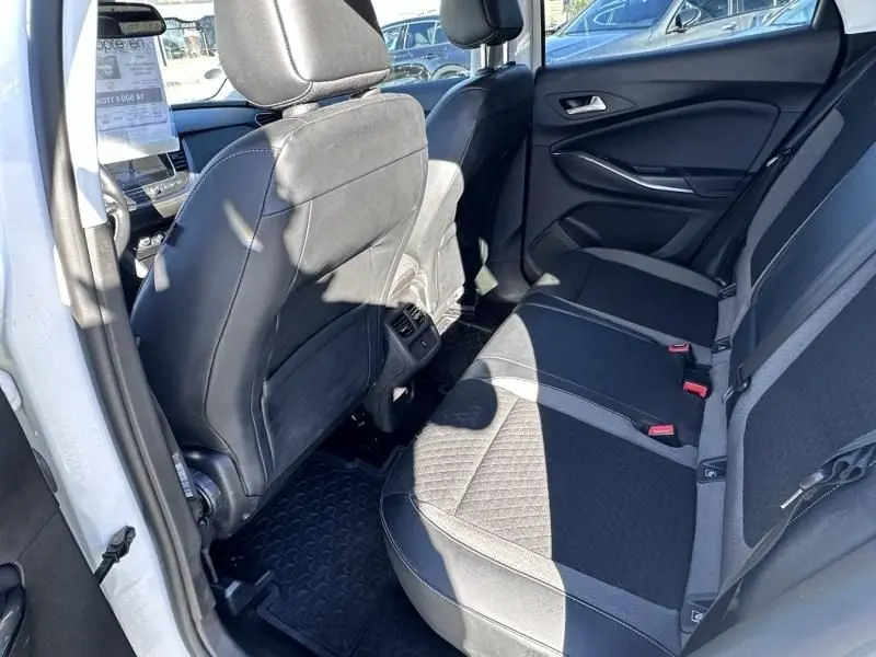Vue intérieure arrière côté gauche de l'Opel Grandland X blanc 2018, montrant les sièges arrière en tissu noir et gris.