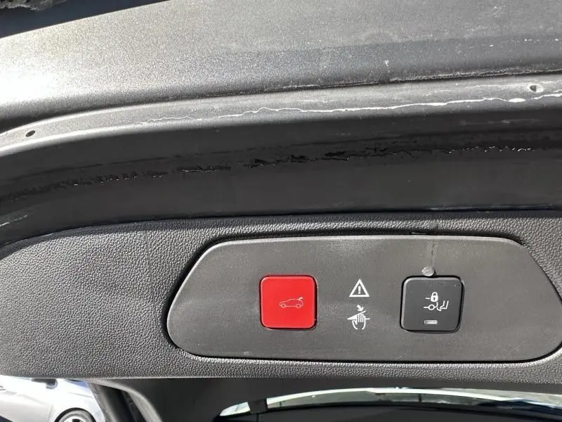 Détail du panneau de commandes sur le hayon intérieur d’un Opel Grandland X blanc, boutons rouge et noir visibles.