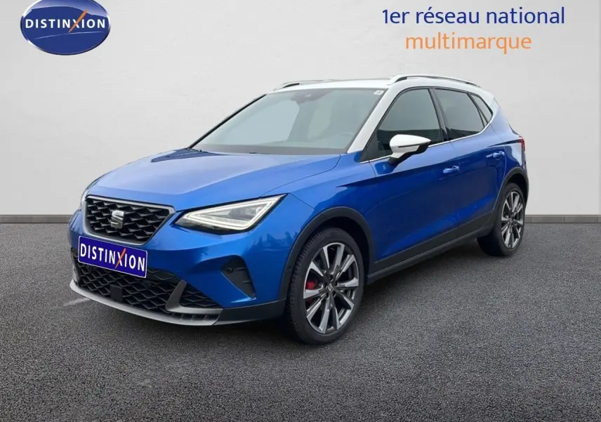 SEAT Arona 2025 bleu saphir métal avec toit blanc, vue 3/4 avant droit, jantes alliage et calandre distinctive.