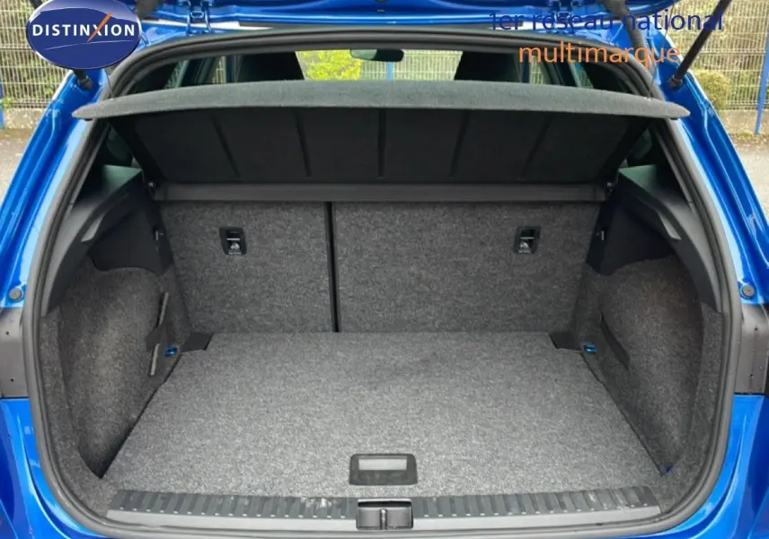 Coffre ouvert vu de l'arrière d'une SEAT Arona bleu saphir métal, montrant l'espace de chargement vide.