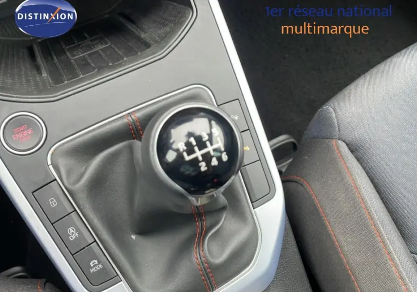 Gros plan sur le levier de vitesses manuel avec coutures rouges, siège tissu gris et bouton Start Engine dans un SEAT Arona 2025.