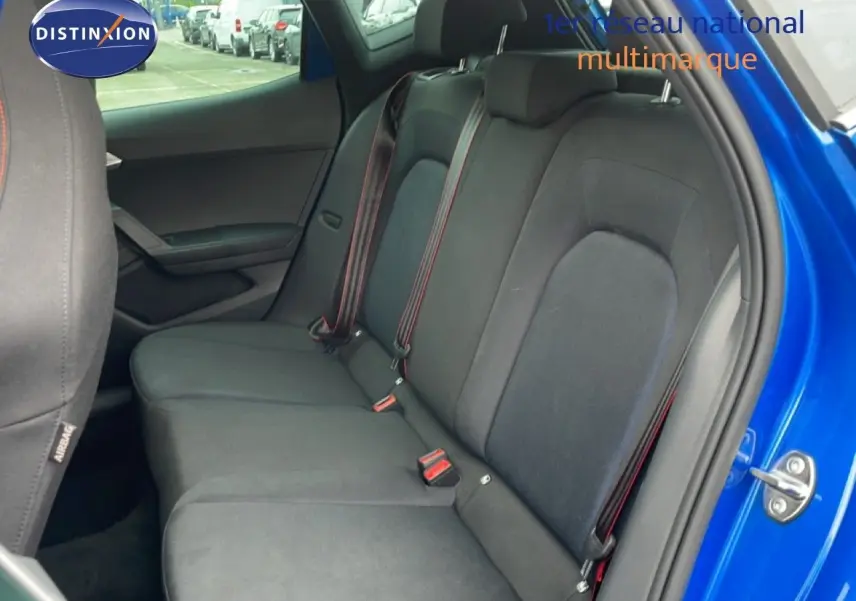Vue intérieure côté droit sur la banquette arrière en tissu noir avec ceinture rouge d’un SEAT Arona bleu saphir 2025.
