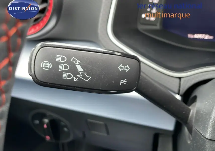 Gros plan sur la manette de clignotant à gauche dans l’habitacle d’un SEAT Arona bleu saphir métal avec toit blanc.