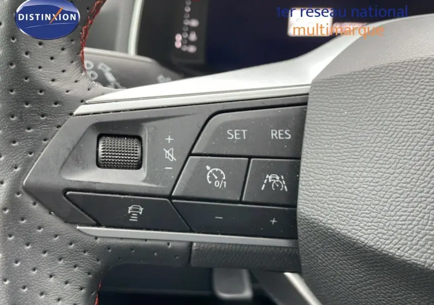 Gros plan sur les commandes de régulateur de vitesse au volant perforé d’une SEAT Arona 2025 finition FR bleu saphir.