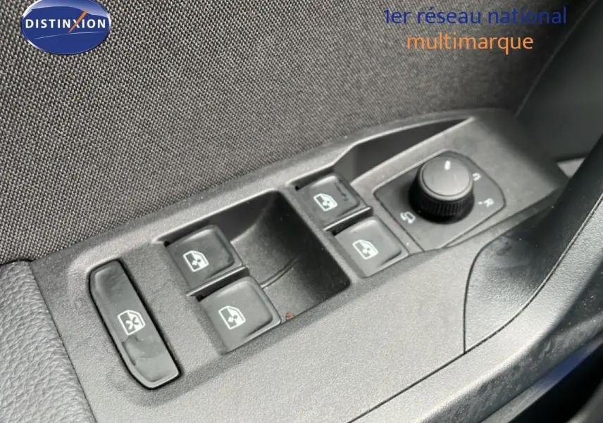 Gros plan sur les commandes des vitres électriques et réglage des rétroviseurs côté conducteur d'une SEAT Arona bleu saphir toit blanc.