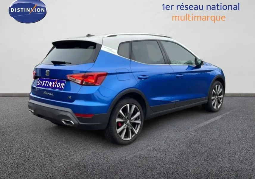 Vue 3/4 arrière droite d’un SEAT Arona bleu saphir métal avec toit blanc et jantes alliage 18 pouces.