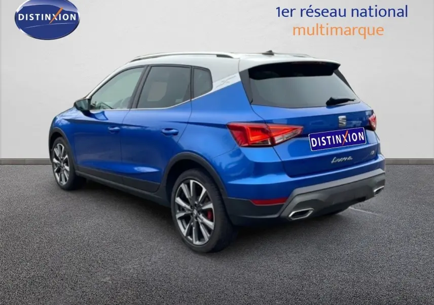SEAT Arona bleu saphir métal avec toit blanc, vue 3/4 arrière droit, jantes alliage et feux arrière LED visibles.