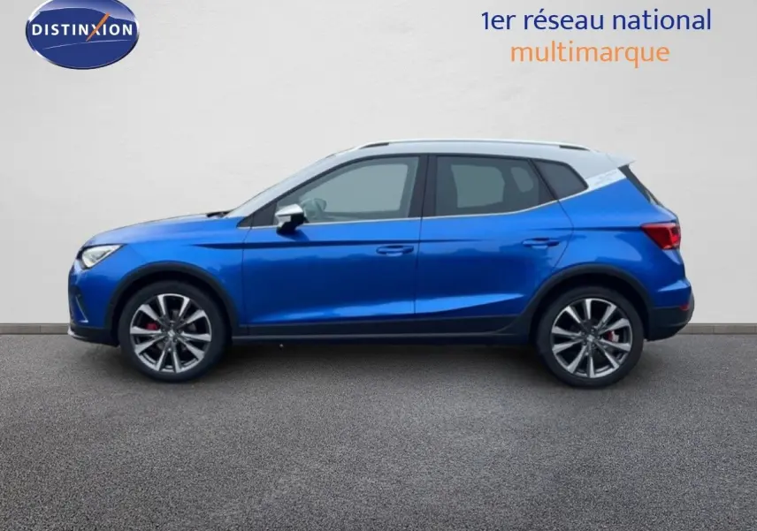 Vue de profil côté gauche d’un SEAT Arona 2025 bleu saphir métal avec toit blanc et jantes alliage.