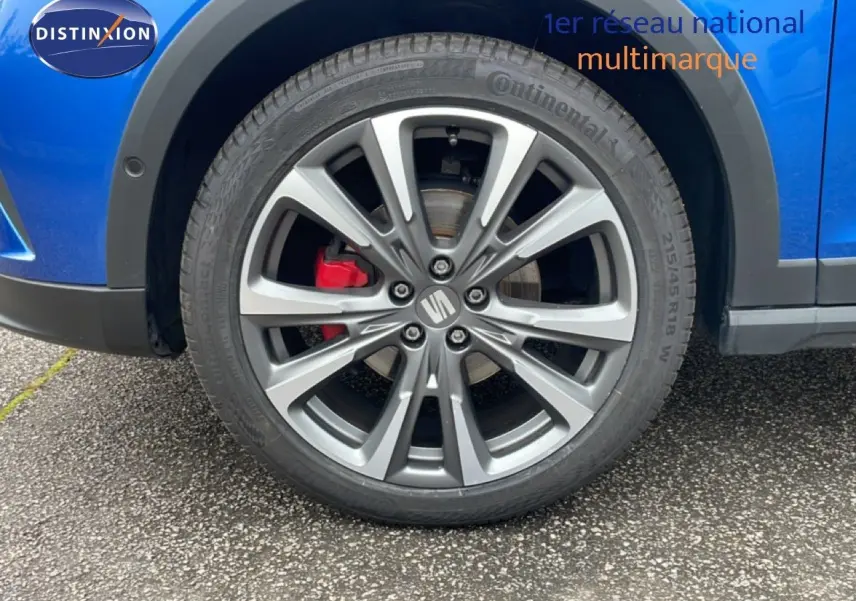 Gros plan sur la roue avant droite d'une SEAT Arona bleu saphir avec étrier de frein rouge et jante alliage.