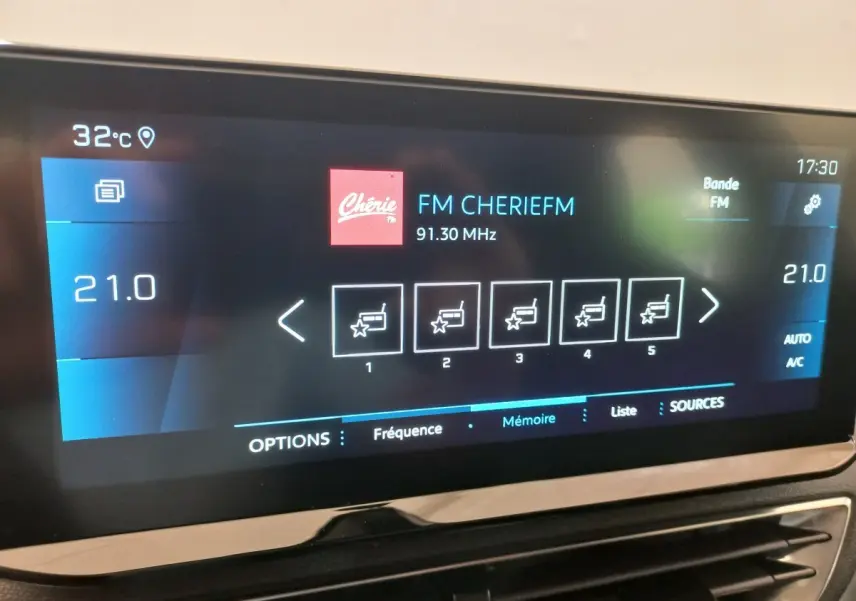 Écran tactile central du Peugeot 3008 noir, affichant la radio FM et la température intérieure à 21°C.