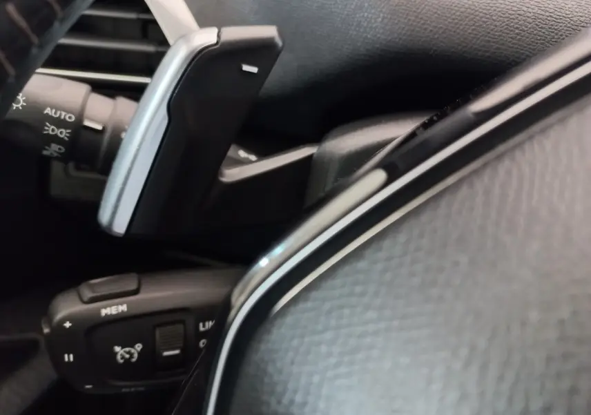 Gros plan sur les commandes au volant cuir noir du Peugeot 3008 PureTech 130, avec régulateur de vitesse et palettes.