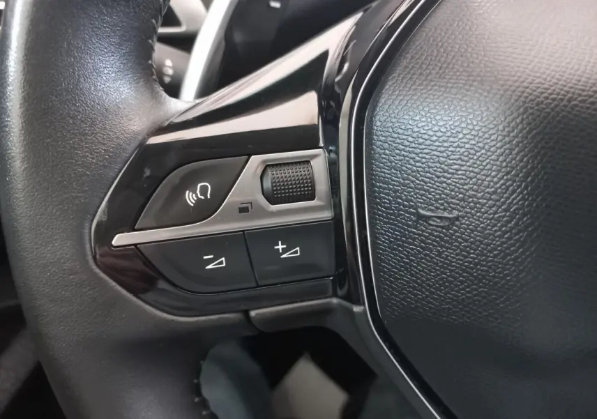 Gros plan sur les commandes gauche du volant noir du Peugeot 3008 2022, avec boutons de volume et commande vocale.