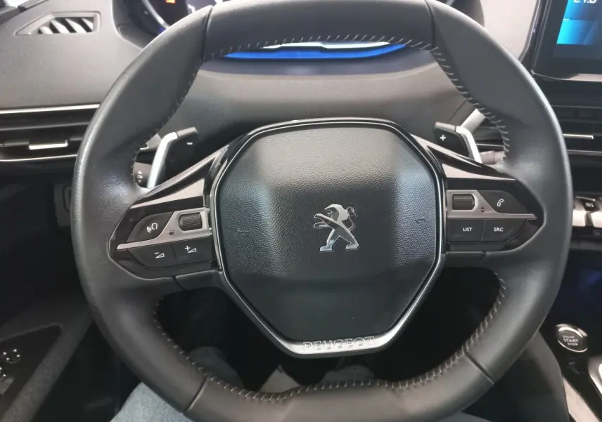 Vue rapprochée du volant cuir noir de la Peugeot 3008 avec commandes multifonctions et logo lion central.
