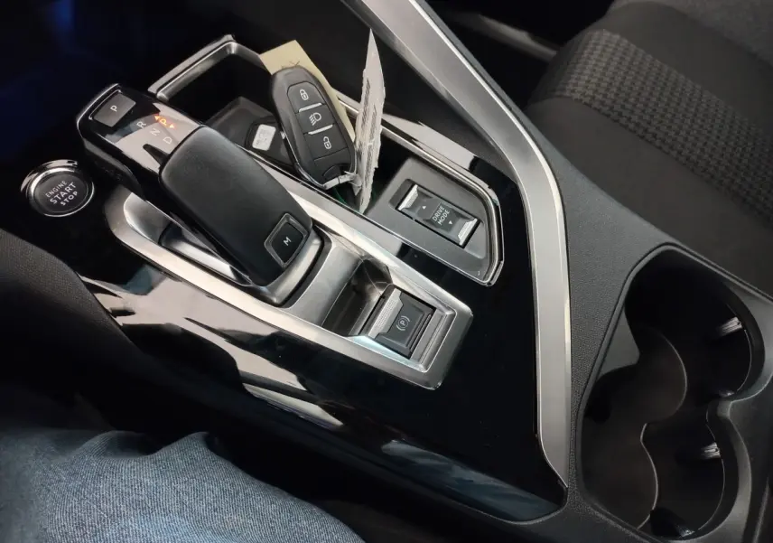 Gros plan sur la console centrale noire du Peugeot 3008 avec levier de vitesse automatique et clé intelligente posée.