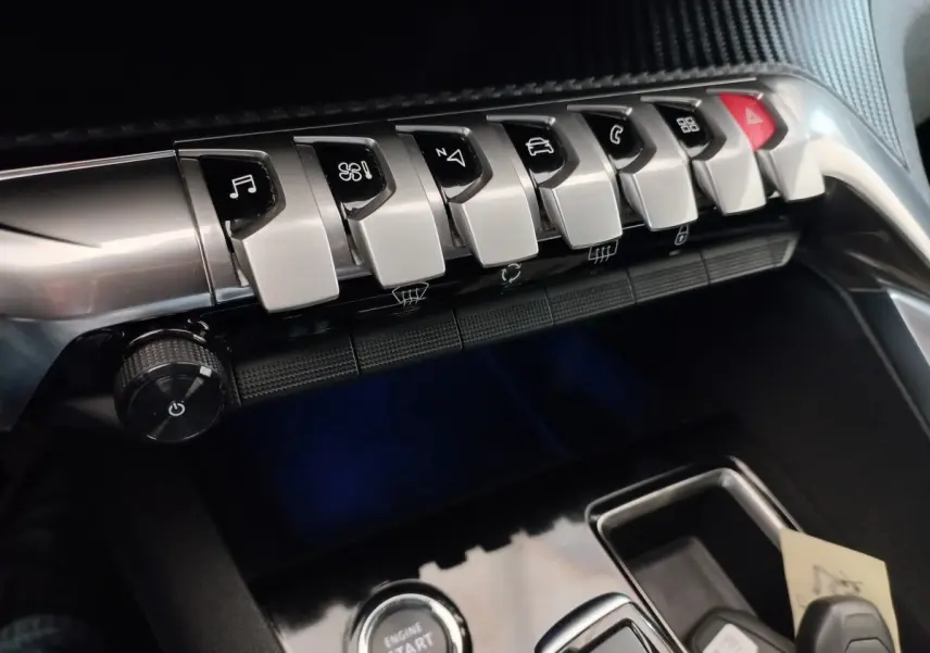 Gros plan sur la console centrale du Peugeot 3008 noir, montrant les boutons de commande et le bouton démarrage.