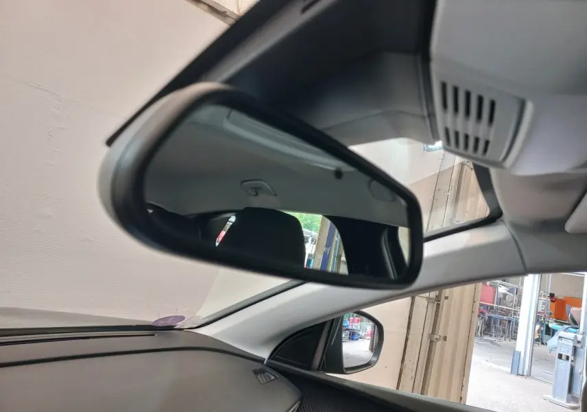 Vue intérieure du rétroviseur central d'un Peugeot 3008 noir 2022, avec partie du tableau de bord et vitre côté droit visibles.