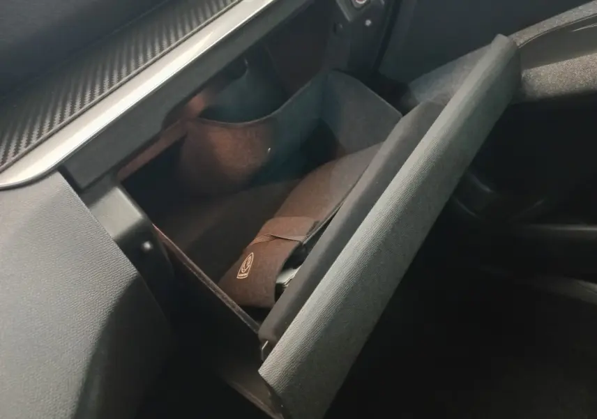 Vue intérieure du vide-poche passager ouvert du Peugeot 3008 noir 2022, avec pochette et éclairage doux.