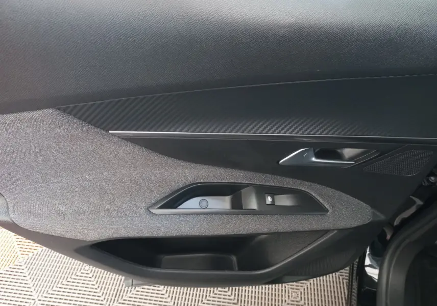 Gros plan sur la porte intérieure côté gauche du Peugeot 3008 noir, montrant la poignée et les commandes de fenêtre.