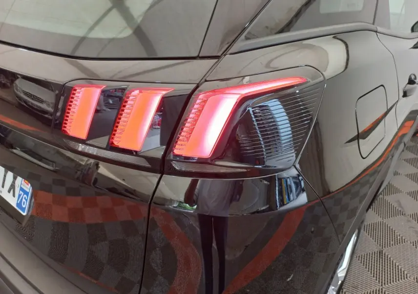 Gros plan sur le feu arrière droit rouge vif d’un Peugeot 3008 noir, mettant en valeur la carrosserie brillante.