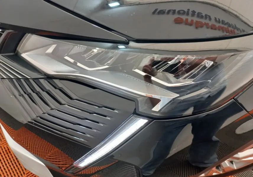Gros plan sur le phare avant droit et la calandre noire brillante d’un Peugeot 3008 2022 PureTech.