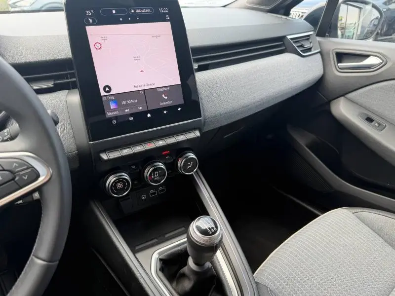 Vue intérieure côté passager de la Renault Clio gris schiste 2025 avec écran tactile vertical et boîte manuelle.