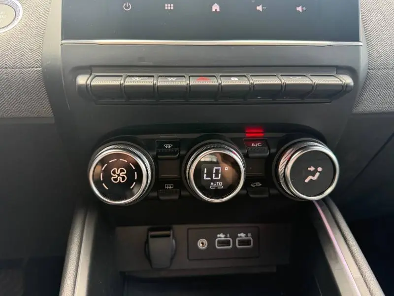 Vue rapprochée du tableau de bord de la Renault Clio gris schiste, montrant les commandes de climatisation et les ports USB.