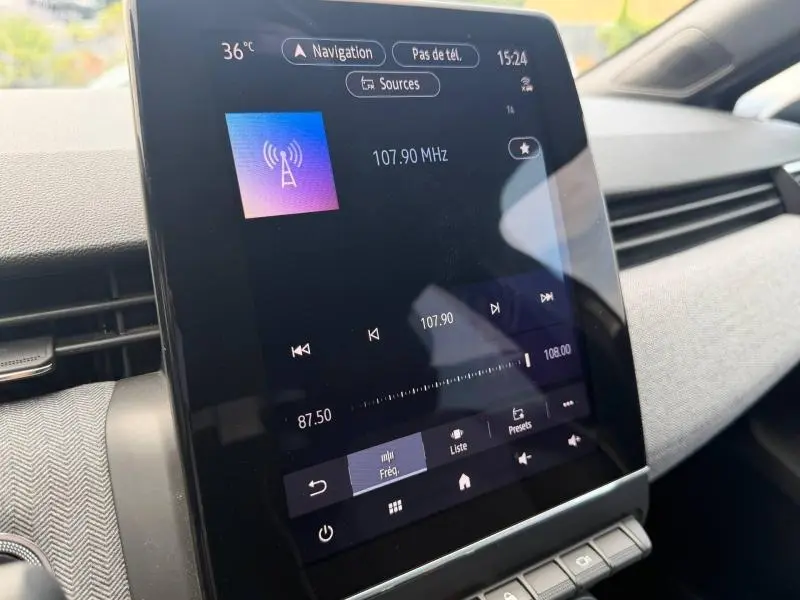 Vue rapprochée de l'écran tactile central de la Renault Clio 2025 gris schiste, affichant la radio FM à 107,90 MHz.