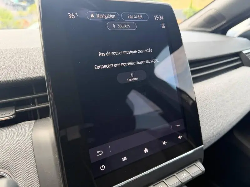 Vue rapprochée de l'écran tactile central du tableau de bord de la Renault Clio gris schiste 2025, affichant le menu de connexion musicale.