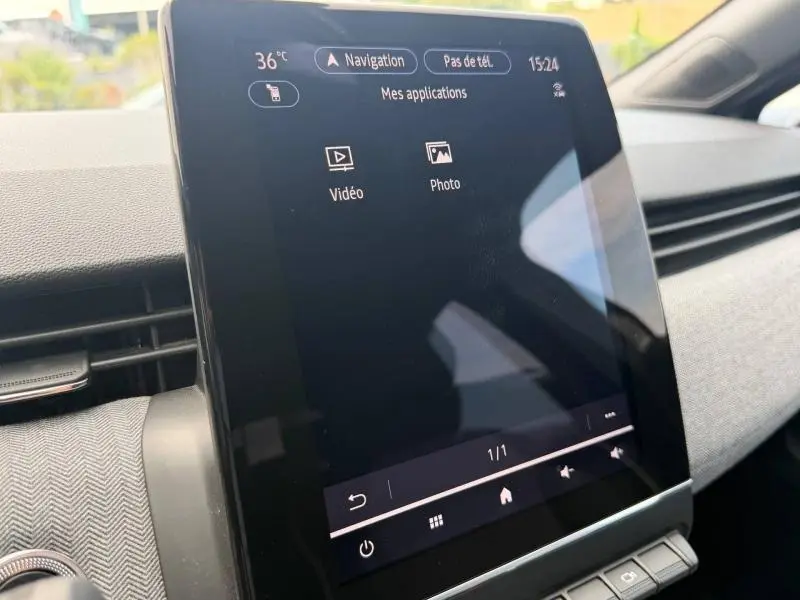 Vue rapprochée de l'écran tactile central du tableau de bord de la Renault Clio gris schiste, affichant les applications multimédia.