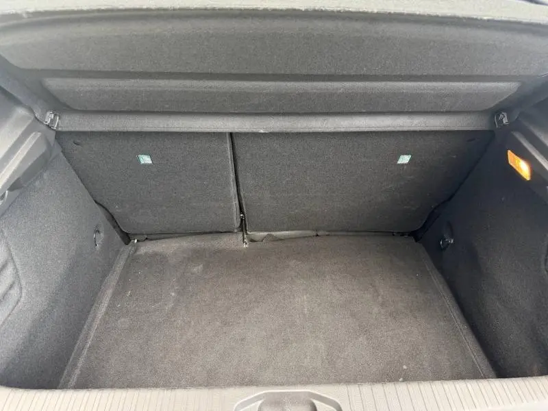 Vue intérieure du coffre spacieux et propre de la Renault Clio gris schiste, avec banquette arrière rabattue partiellement.