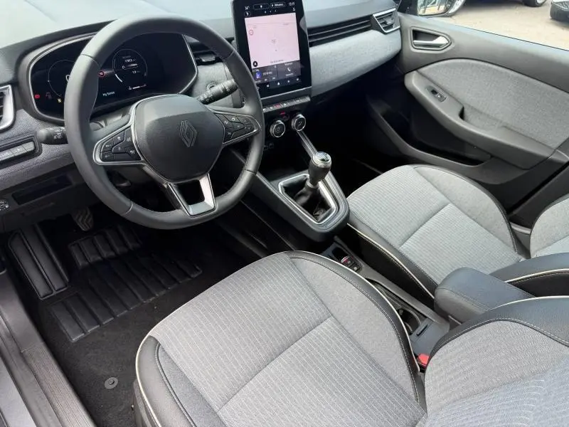 Intérieur Renault Clio 1.0 Eco-G 2025 vu côté conducteur, sièges gris, volant multifonction et écran tactile vertical.