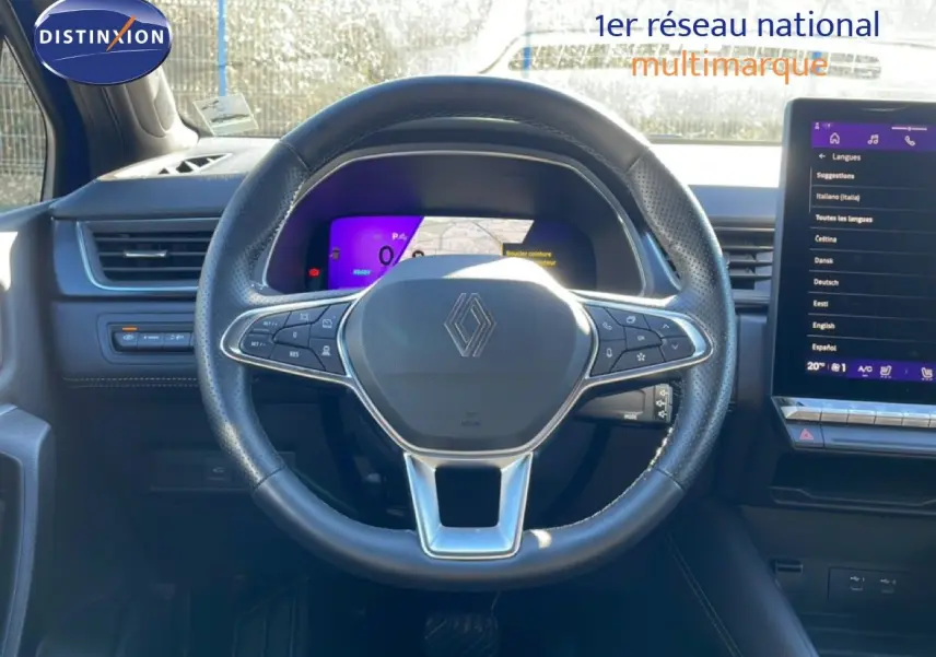 Vue intérieure centrée sur le volant noir perforé avec logo Renault, tableau de bord digital et écran tactile à droite.