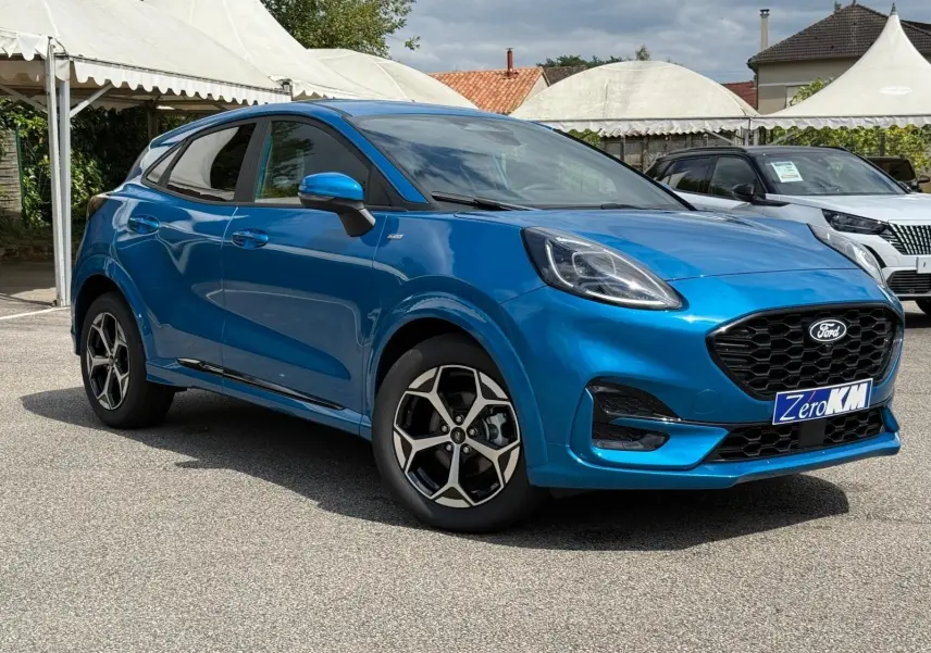 Ford Puma 2025 bleu Aqua Blue en 3/4 avant droit, avec jantes alliage et calandre noire distinctive.