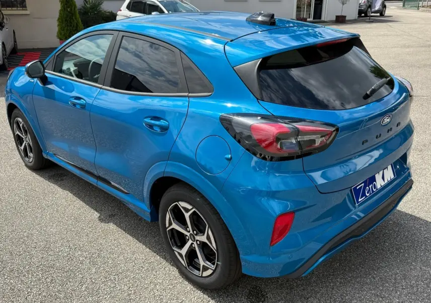 Ford Puma 2025 bleu Aqua en vue 3/4 arrière droit, avec feux arrière fumés et jantes alliage noires.