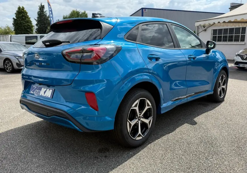 Vue 3/4 arrière droite d'un Ford Puma 2025 bleu Aqua avec jantes alliage et vitres teintées.