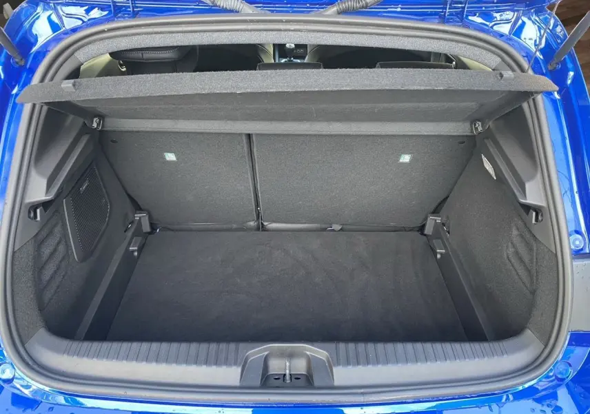 Coffre ouvert vu de l'arrière d'une Renault Clio V TCE 90 Esprit Alpine en bleu Iron, intérieur noir et tapis de coffre.