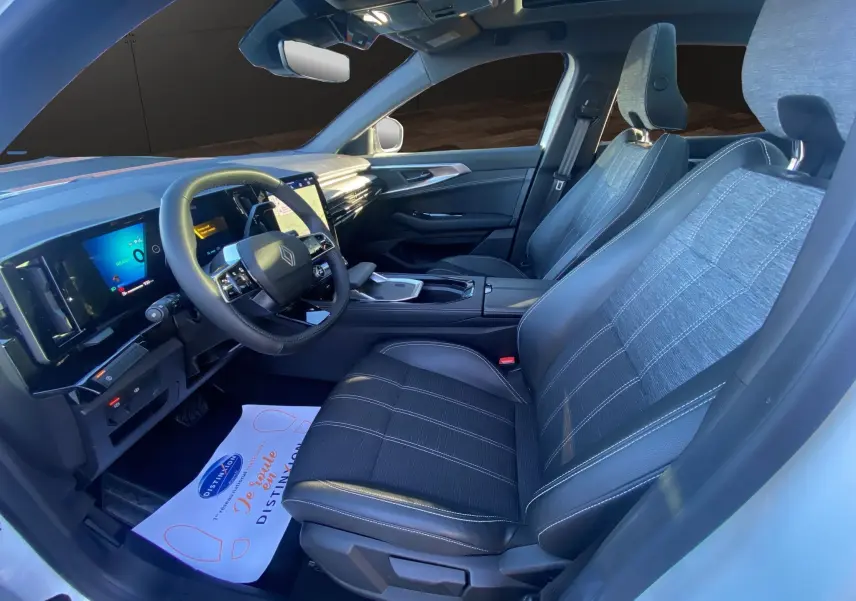 Vue intérieure côté conducteur du Renault Austral 2025, sièges tissu et cuir noirs, toit panoramique visible.